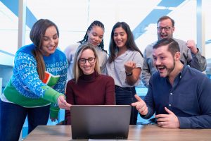 pessoas reunidas na frente de um notebook fazendo networking