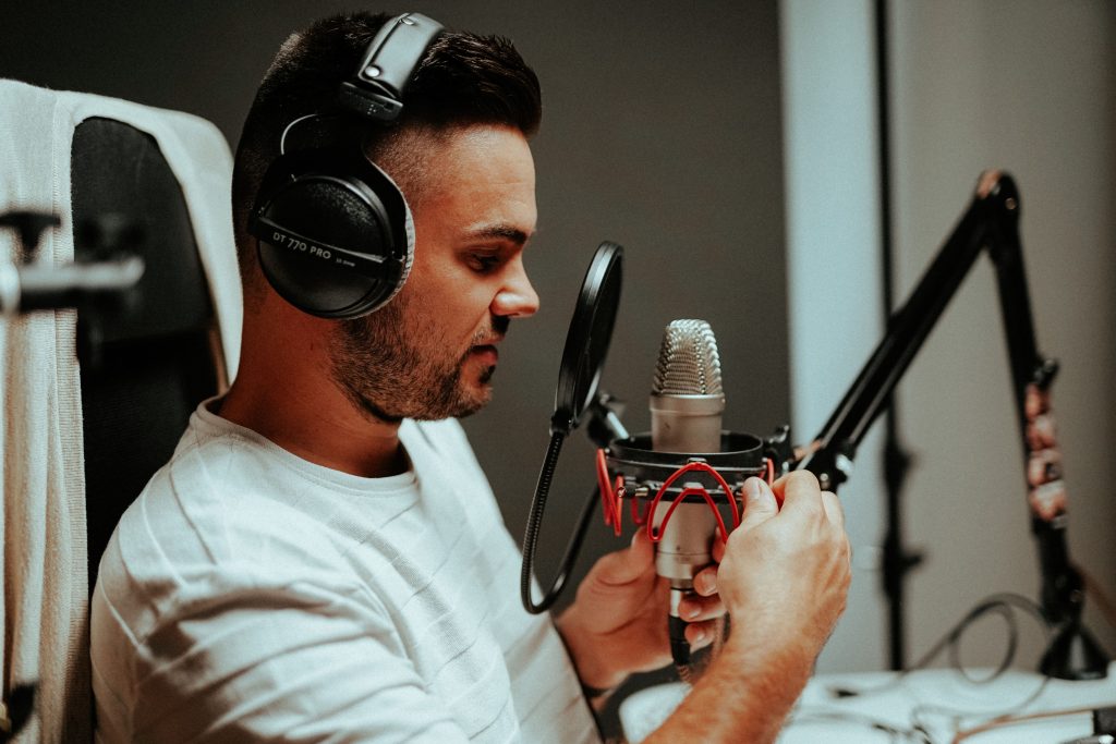 Homem em um estúdio com um fone e um microfone gravando para eventos online