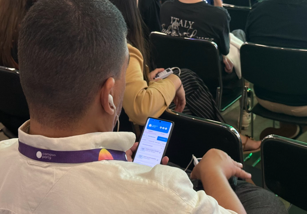 Participante manuseando o celular com um aplicativo personalizado para eventos.